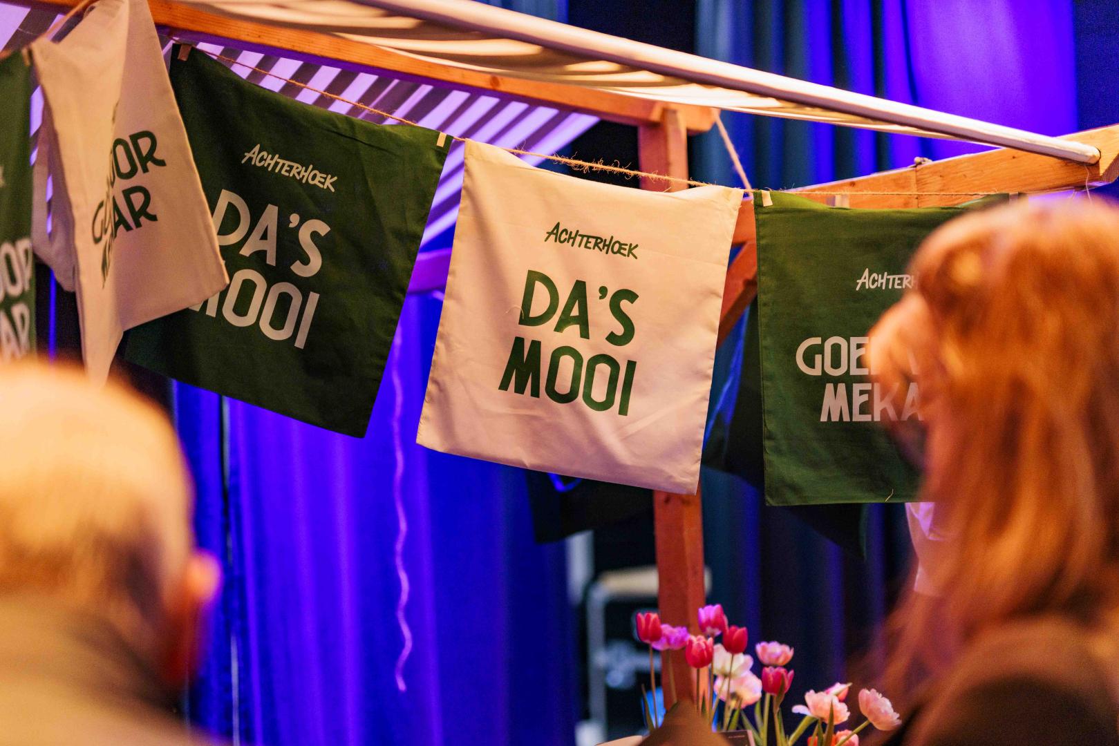Aan een marktkraam hangen tasjes van Achterhoek Toerisme met de tekst 'Da's mooi'.